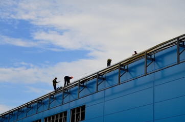 Naklejka premium workers on the roof of the building with insurance perform work on the construction of the building