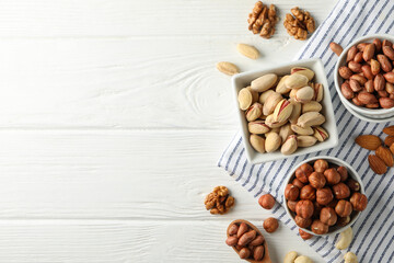 Bowls with different nuts on white wooden background. Vitamin food