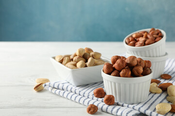 Bowls with different nuts on white wooden background. Vitamin food