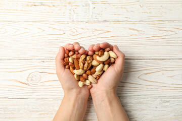 Woman holds different nuts on wooden background. Healthy eating