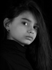 Closeup portrait of serious little girl isolated on black background.monochrome