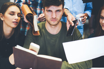 Serious confident busy male business coach checking business plans of crew of male and female...