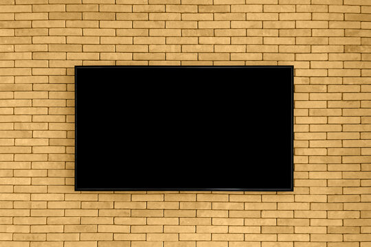 Blank black tv on the brown brick wall with copy space. TV display on old brick wall background. Mockup.
