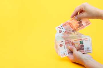 Hands put another bill in a pack of five thousandth bills