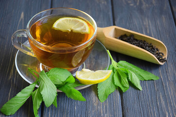 Cup of fragrant black tea with honey on a dark background