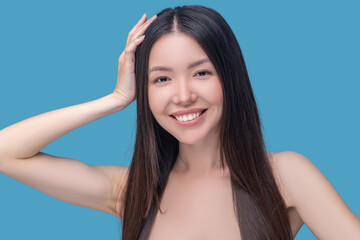 Fototapeta premium Smiling dark-haired woman touching her beautiful hair