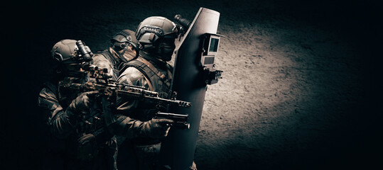 Image of three soldiers in a shooting computer game. ESports concept. They hide behind a tactical...