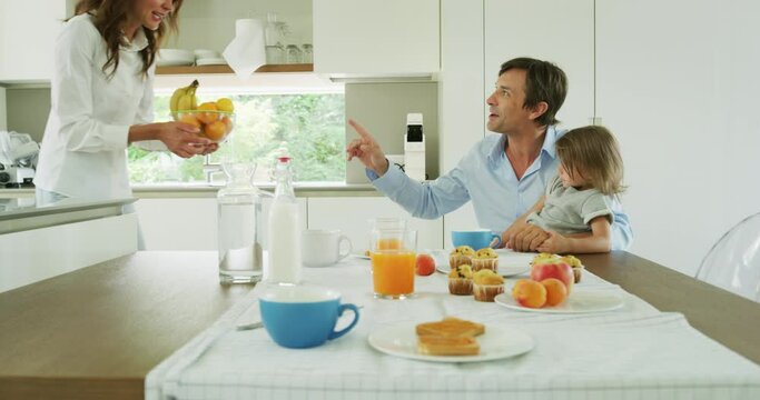 Authentic shot of a happy smiling family is enjoying their time together while having a breakfast in a kitchen at home in the morning.