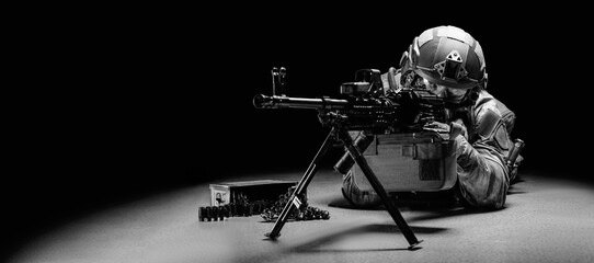 Portrait of a fighter of a special unit. He lies on the ground and shoots from a heavy machine gun....
