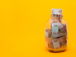 Five thousandth bills lie in a glass jar, a bill sticks out of the jar