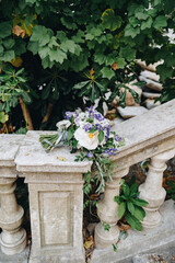 Fototapeta na wymiar bridal bouquet of white roses, branches of eucalyptus tree and tender blue flowers on the railing of an ancient staircase