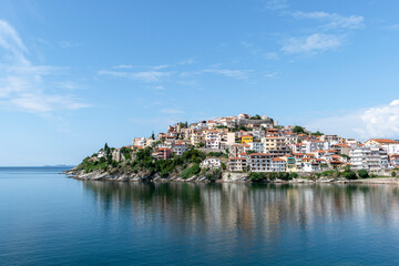 Fototapeta na wymiar Colorful view of greek city of Kavala on sunny summer day. The old city and its reflection in calm sea. Northern Greece, Eastern Macedonia, Europe. Popular tourist destination. Copy space