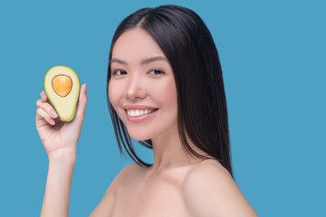 Smiling woman holding a piece of avocado
