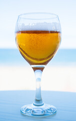 Glass of beer on a blurred blue background of sea. Shallow depth of field