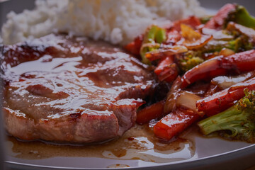 Pork shoulder steak with stir-fried vegetables and rice.