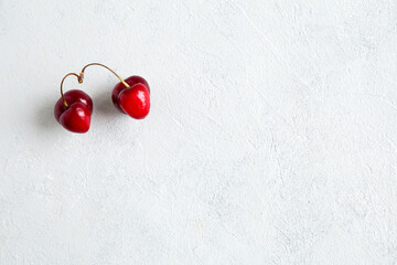 Pair of strange, ugly cherries in the heart shape on a white background. Trendy ugly organic product. Malformed berry. Funny, unnormal berry or food waste concept. Horizontal, flat lay, copy space.