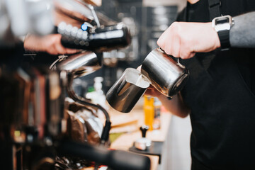 Barista professional pours milk from a pitcher - adding milk to coffee