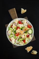 Salad fattoush with pita bread, fresh vegetables on the white plate on the wooden stand. Traditional middle eastern or arabic food. Vegetarian snack. Close up, top view, dark background, flat lay.