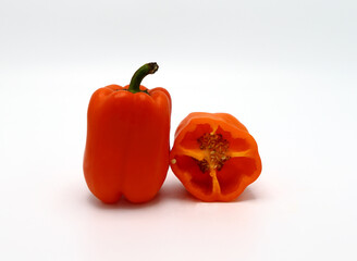 Red ripe sweet peppers and half orange on a light background. Natural product. Natural color. Close-up.