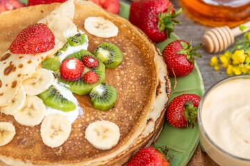 Pancakes with strawberries, kiwi, honey and banana for summer Breakfast.  Children's pancake Breakfast.