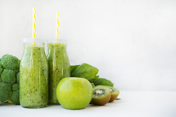 Vegetarian green smoothie with vegetables and fruit in glass bottles, copy space