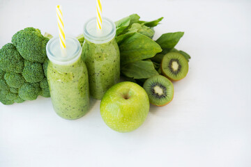 Vegetarian green smoothie with vegetables and fruit in glass bottles, copy space