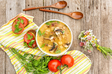 Vegetarian potato soup with mushrooms and croutons on a wooden background. Delicious vegetarian lunch with soup and bread with herbs and tomato.