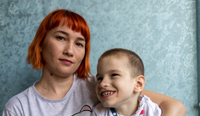 Boy with cerebral palsy and his mom in the conditions of his apartment. Boy reacts vividly to everything that happens around him and shows it with his personality. High quality photo