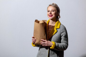 girl in gray coat and vintage hairdress with supermarket paper bag