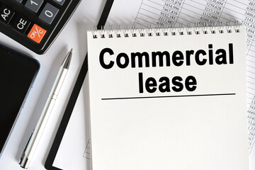 On the table lies a smartphone, a calculator and a notebook with the inscription - Commercial lease.