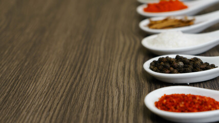 pimienta negra en granos y otras especias en cucharas de porcelana 