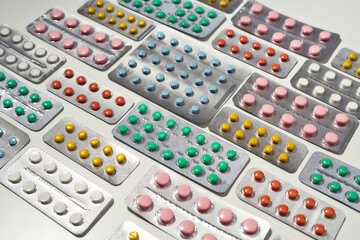 Composition with many medical pills, tablets pack in blister lying diagonally over white background. Health care, vitamins and treatment concept