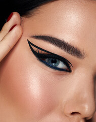 Naklejka premium Beautiful woman portrait with fresh daily make-up black hair and healthy skin. perfect eyeliner arrows. Eyebrows Care. Closeup Of Woman Beautiful Blue Eye, Perfect Shaped Brow, Long Eyelashes 