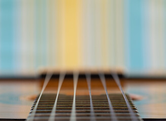 Fototapeta premium Perspective closeup of the strings of a guitar moving towards a background of colored vertical lines