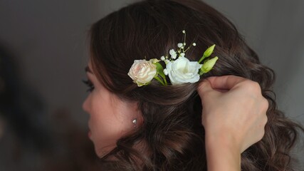 Naklejka premium The stylist adorns the girl's hair with delicate flowers.