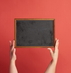 woman hands holds brown empty wooden frame on red background