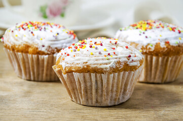 Tasty curd muffins with multi-colored caramel close-up on a wooden board, selective focus. Sweet dessert. Baking is ready for sale at the store.