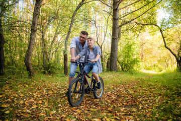 Fototapeta na wymiar Father teaches son to ride the bicycle