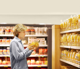 Young man shopping in supermarket, reading product information	