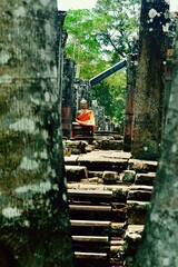 Beautiful Buddha statue draped in orange robe while wandering acient Angkor, Siem Reap Cambodia