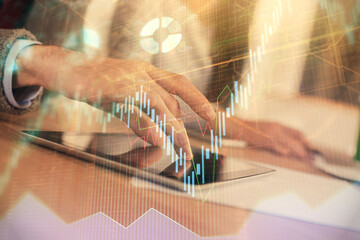 Double exposure of forex graph drawing and man and woman working together holding and using a mobile device. Trade concept.