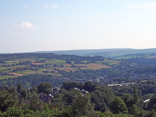 a panoramic view west yorkshire countryside with the village of warley surrounded by woodland and farmland with pennine hills in the distance