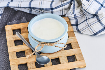 Fototapeta na wymiar Greek yogurt in a ceramik blue bowl with a spoon on a wooden stand, rustic style
