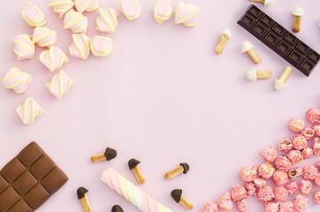 top view, flat lay, frame on set of different sweets, candies, marshmallow, chocolate, popcorn on pink background, copy space, text. The concept of female, children's holiday, diet, junk food.