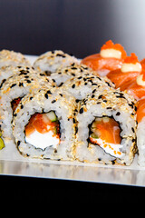 Japanese sushi food. Assorted rolls philadelphia with wasabi and white ginger of tha white plate. Rolls with tuna, salmon, sesame. Vertical view