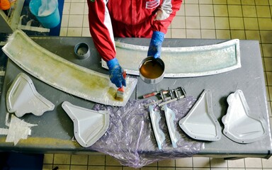 Installation of fiberglass: worker manually realizes a component in glass fiber for automotive use....