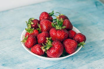 Eco or Bio Strawberry in White Bowl on Turquoise Table Side View Still-Life Shot with Natural Light