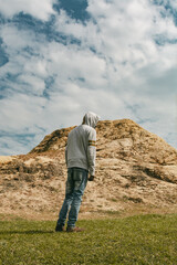 Young black man walking towards a hill wearing a hoodie