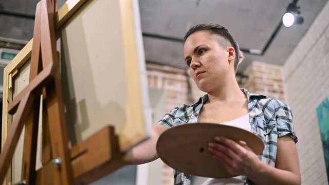 Bottom view of a woman who is painting in a studio. enthusiastic artist at work