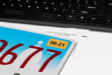 Vehicle license plate, renewal sticker, computer keyboard and registration card. Concept of state government automobile fees, transportation taxes, funding and online renewal